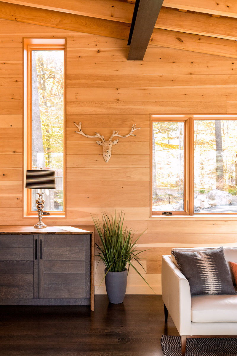  A detail of the living room showing pine walls and the edge of a custom sideboard whose white oak drawers are stained the same custom blue-black used on kitchen cabinetry and elsewhere in the house. 