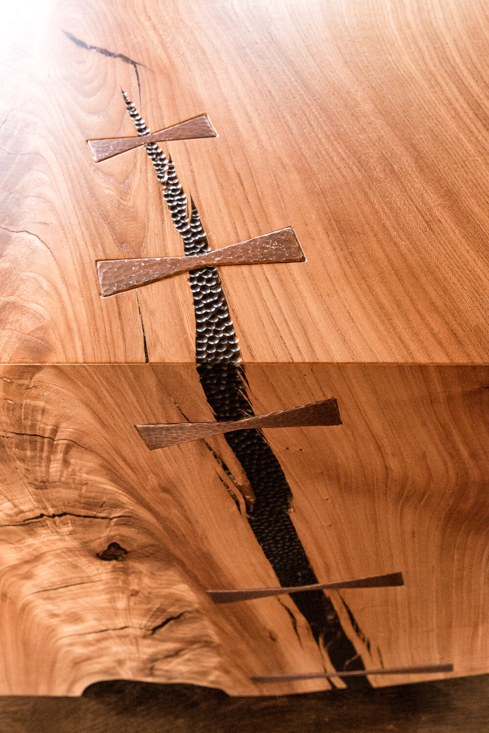  A crack in the kitchen island was filled with black epoxy, which was then hammered and spanned with copper bow ties. 