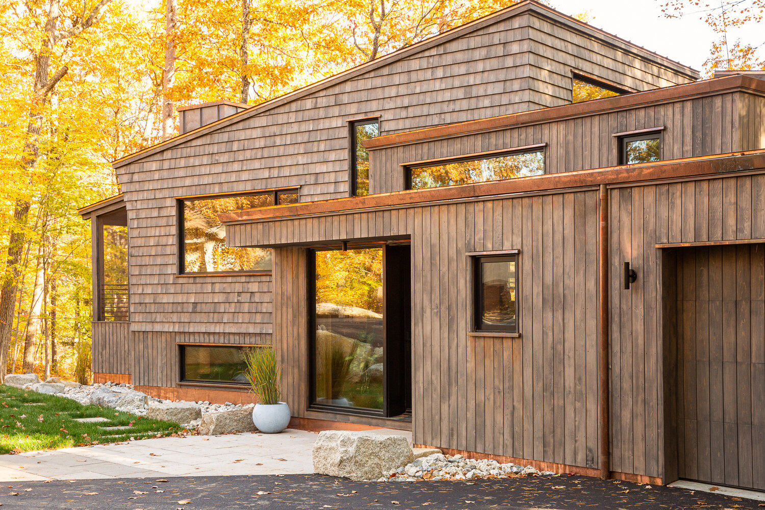  Front entry with copper detailing shows cedar planks on the flat roof forms in the foreground and cedar shakes under the slanting roof behind. 