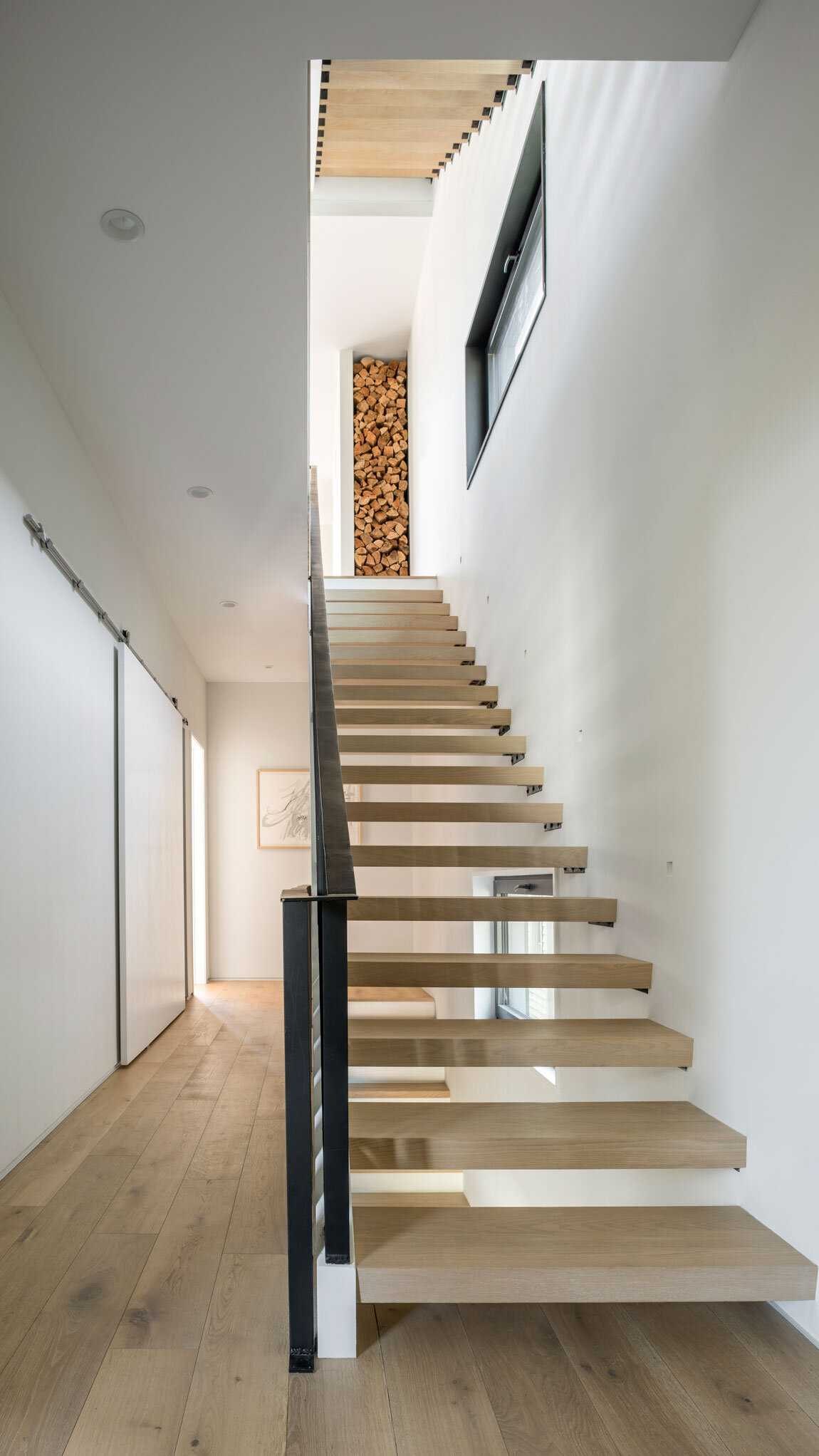  The open-tread staircase is braced by a matte-black steel banister. 