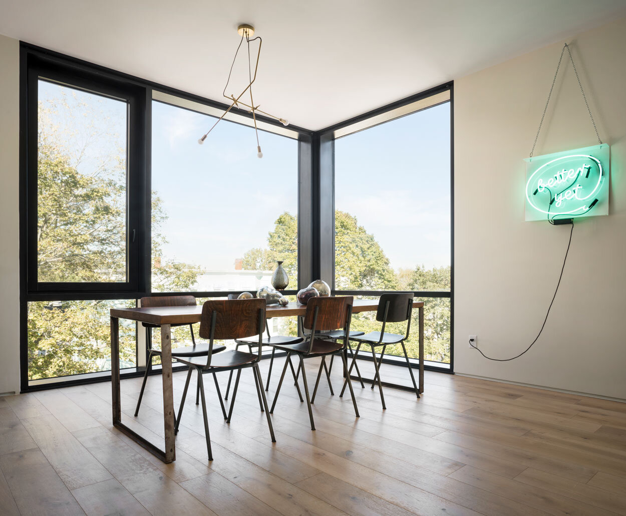  The walnut table, handmade by the couple, is framed by vintage Dutch chairs under a Lambert &amp; Fils light fixture. The neon sign depicts Kate’s company logo. 