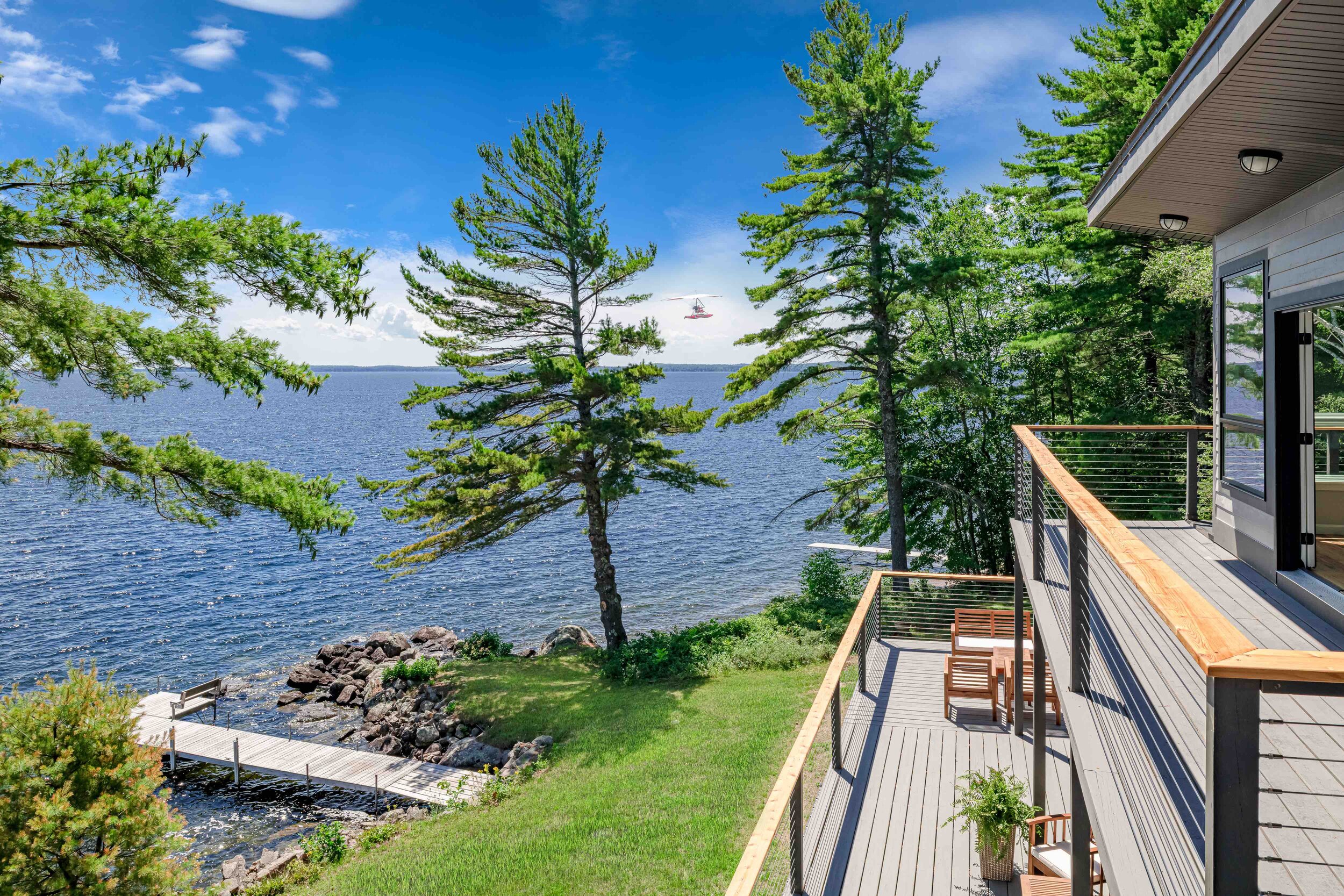  From the balconies, the idyllic scene comprises swaying conifers, crystalline waters, and a light-sport airplane in the distance. 