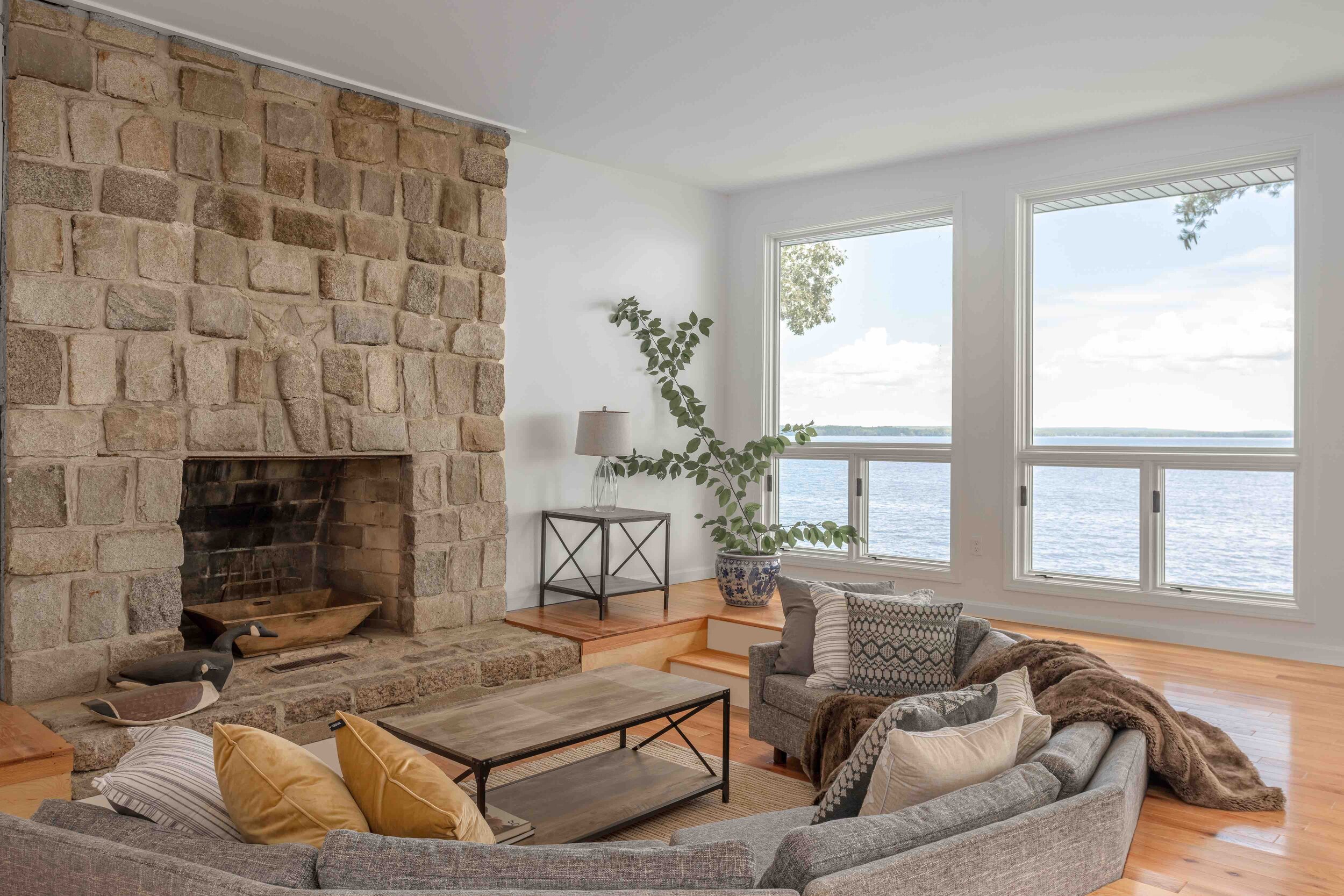 In the living room, the home’s original stone fireplace and dropped-level sofa—modernly reupholstered by Claude’s Upholstering—create a comfort- able space to talk and unwind.