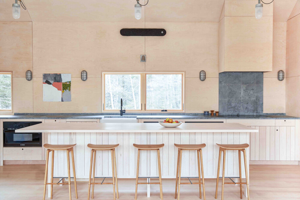 Maple rough-sawn cabinets are paired with untreated soap- stone counters and tile from Vermont Soapstone. Cabinet fronts conceal Miele appli- ances, making for a spruce appearance.